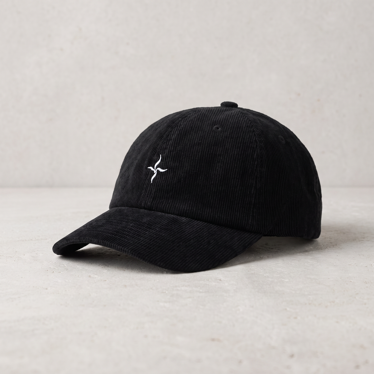 VEYR Field Cap in Black on pale stone, editorial view